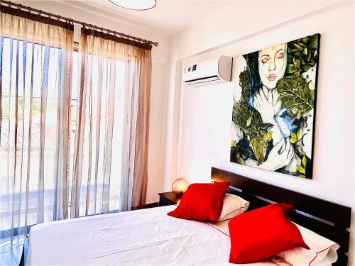 a bedroom with a large painting above a bed with red pillows at BALI SUITES 101 in Larnaka