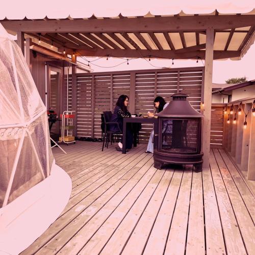 two women sitting at a table on a deck with a grill at Necoana Glamping Annovillasグランピング in Fujikawaguchiko