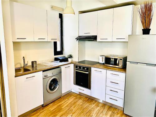 uma cozinha com armários brancos e uma máquina de lavar e secar roupa em BALI SUITES 303 em Lárnaca