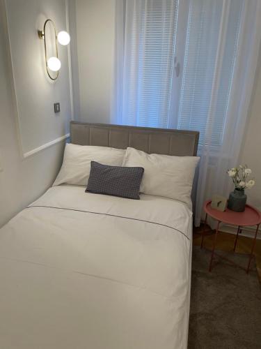 a bed with white sheets and pillows in a room at Apartman Vasia Subotica in Subotica