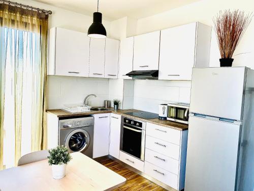 a kitchen with white cabinets and a white refrigerator at BALI SUITES 505 in Larnaka