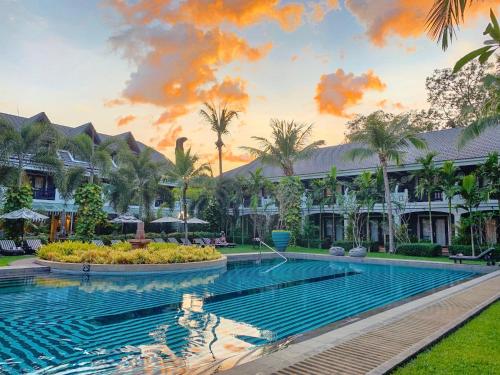 una piscina di fronte a un resort con palme di Shinta Mani Angkor & Bensley Collection Pool Villas a Siem Reap