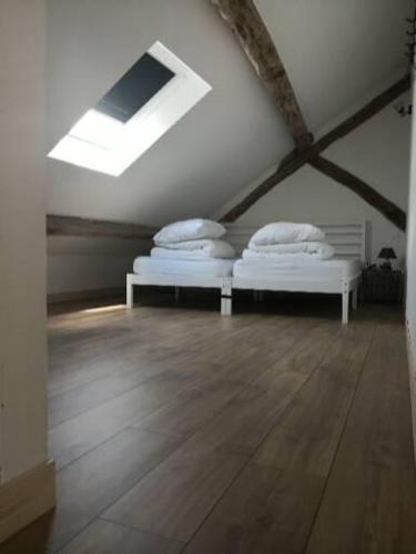 deux lits dans une chambre mansardée avec une lucarne dans l'établissement Le Pressoir-Gîte 2-4 personnes, à Mosnes