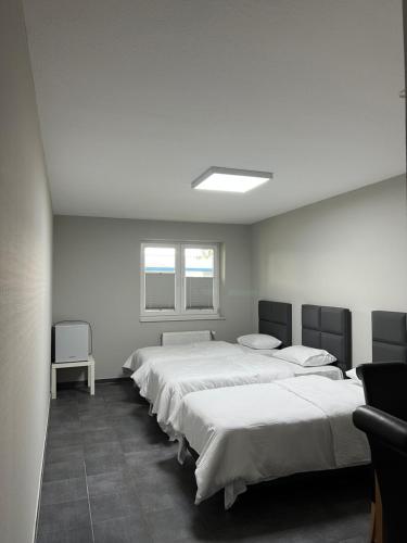 a room with four beds and a window at Motel am Outletcenter in Neumünster