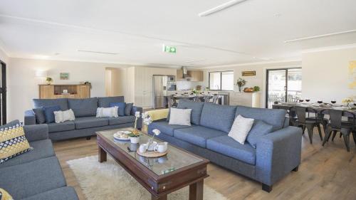 una sala de estar con sofás azules y una mesa. en Sutton Forest Retreat Jimmys Homestead, en Sutton Forest