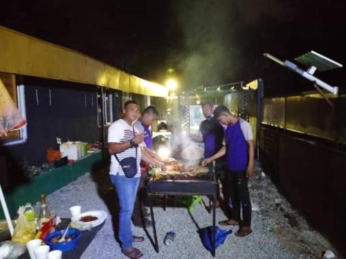 a group of men standing around a barbecue grill at RD Legend Hotel in Port Dickson