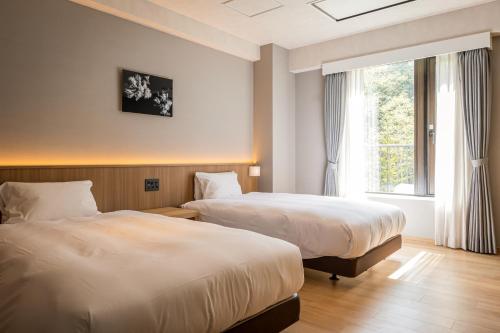 a hotel room with two beds and a window at Higashikawa Asahidake Onsen Hotel Bear Monte in Higashikawa