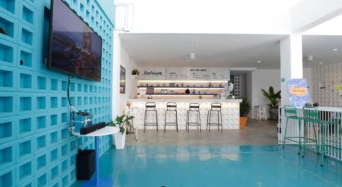 a room with a blue wall with a tv and stools at Borbaboom Phuket Poshtel & Hostel in Phuket