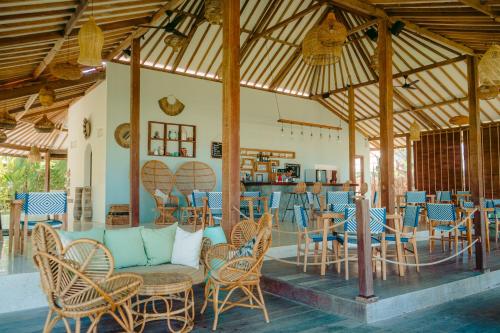 a patio with chairs and tables and a bar at Segara Lombok Beach Resort in Selong Belanak
