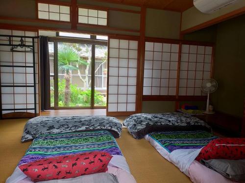 a room with four beds in a room with windows at Neko Neko La Campagne in Tamba