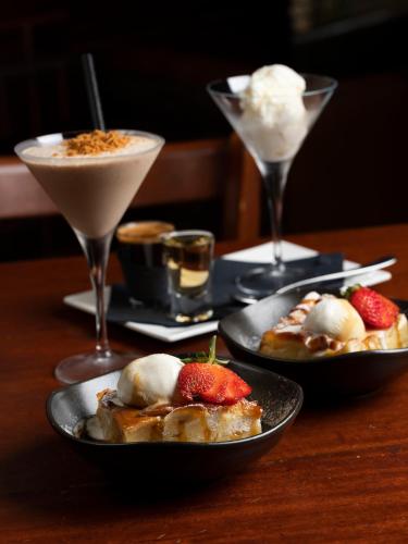 a table with two plates of food and two cocktails at The Tanunda Club Guest Suites in Tanunda