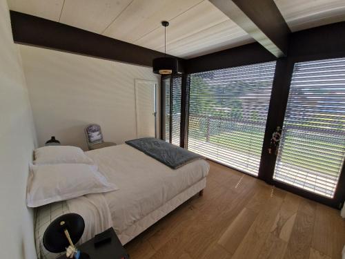 a bedroom with a large bed and large windows at Villa Laba in Yvoire