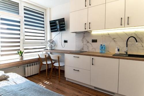 una cocina con armarios blancos y una cama en una habitación en Komfortowe studio ścisłe centrum Radom en Radom
