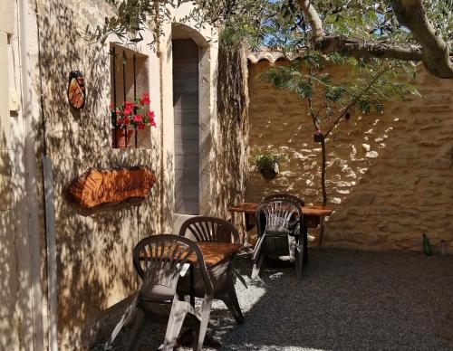 a patio with two chairs and a table and a tree at Les Gîtes sous l' Olivier en Camargue in Vauvert