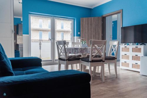 a blue living room with a table and chairs at Pod Brzozami Apartamenty 5 Mórz in Ustronie Morskie