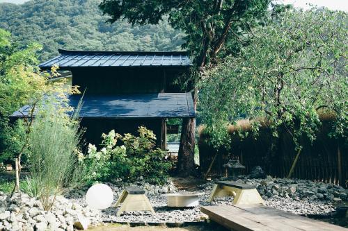 a garden with a wooden bench and a building at Kominkayado LOOF Sawanoie in Fuefuki