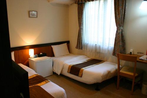 a hotel room with two beds and a desk at Pension Marieペンションマリエ in Yamanakako