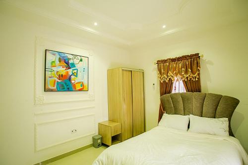 a bedroom with a bed and a painting on the wall at Kiki's Home and Apartments in Magboro-Akeran