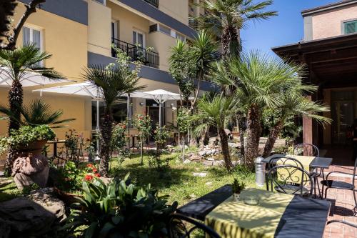 un patio con mesa y sillas frente a un edificio en Hotel Villa Margherita, en Ladispoli