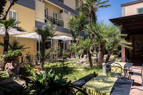 un patio con tavolo e sedie di fronte a un edificio di Hotel Villa Margherita a Ladispoli