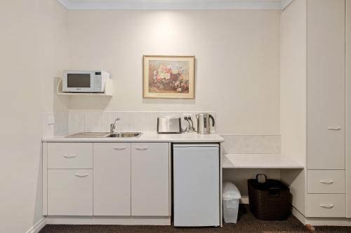 a white kitchen with a sink and a microwave at Yarra Gables in Healesville