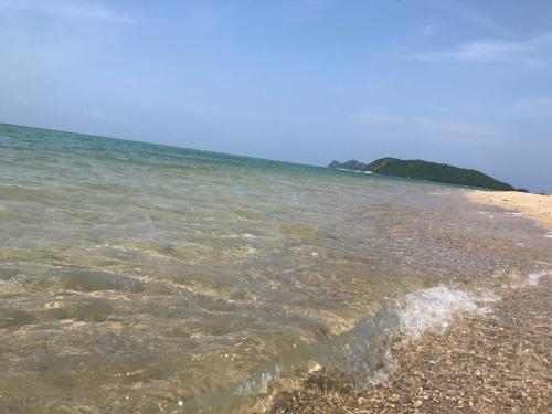a beach with clear water and an island in the background at Phangan Villa Bungalows in Thongsala