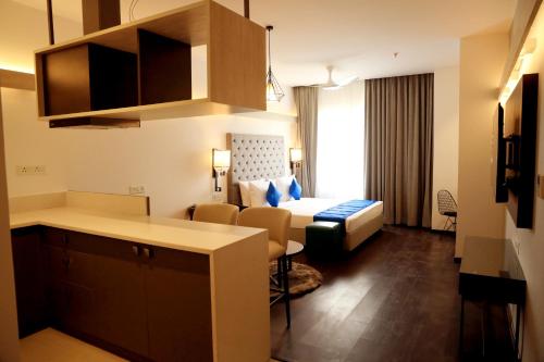 a hotel room with a bed and a kitchen with a table at Hotel Deccan Serai Grande, Gachibowli, Hyderabad in Hyderabad