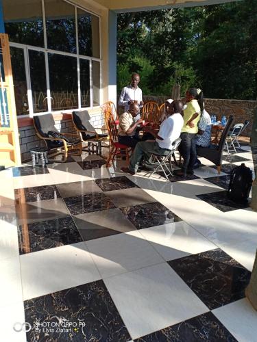 eine Gruppe von Menschen, die auf Stühlen auf einer Terrasse sitzen in der Unterkunft NdamaRosa River Park Resort in Migori