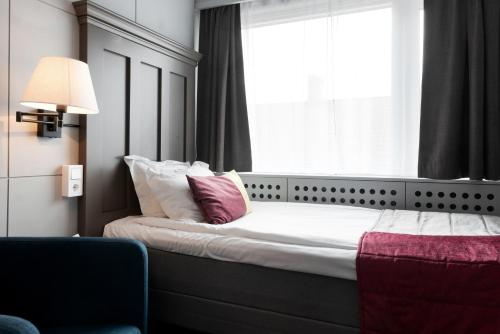 a bedroom with a bed with a large window at Elite Stadshotellet Växjö in Växjö