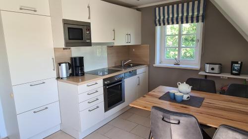 a kitchen with white cabinets and a wooden table at Wohnung Ankerplatz in Wrixum
