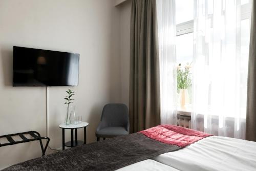a bedroom with a bed and a tv and a chair at Elite Stadshotellet Växjö in Växjö