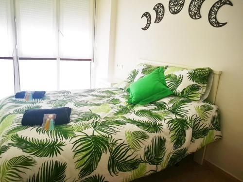 a bedroom with a bed with green palm leaves at ORTEGA SUITE, dúplex en el centro de Luanco in Luanco