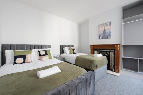 a bedroom with two beds and a fireplace at Stunning 6 Bed House in Medway with 10 beds 4 bathrooms sleeps 15 in Gillingham
