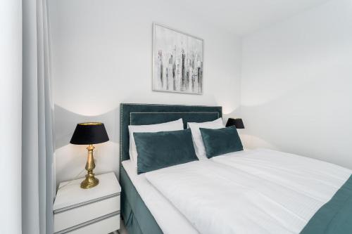 sypialnia z łóżkiem z białą pościelą i niebieskimi poduszkami w obiekcie Apartament DIAMOND w Kołobrzegu