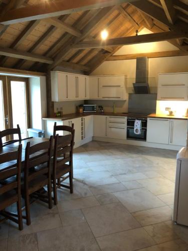 cocina con armarios blancos, mesa y sillas en Old Tynribbie House - Comfortable Detached House, en Appin