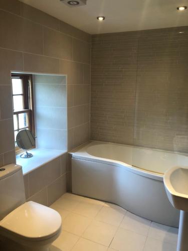 a bathroom with a tub and a toilet and a sink at Old Tynribbie House - Comfortable Detached House in Appin