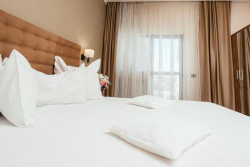 a bedroom with two white beds and a window at C Guest House in Drobeta-Turnu Severin
