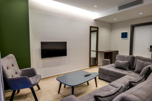 uma sala de estar com um sofá e cadeiras e uma televisão em NERIUM Hotel em Ksamil