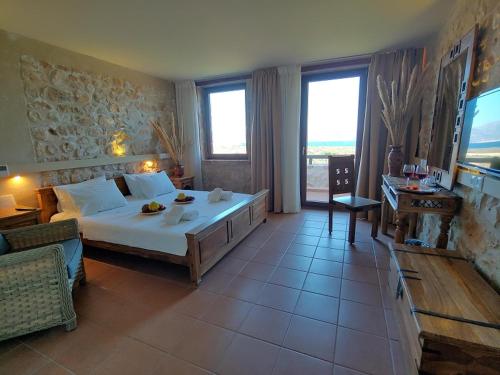 a bedroom with a large bed in a room with windows at Simosmare Resort in Elafonisos
