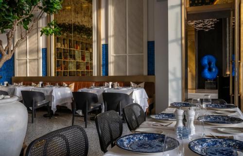 um restaurante com mesas e cadeiras brancas e pratos azuis em Jareed Hotel Riyadh em Riyadh