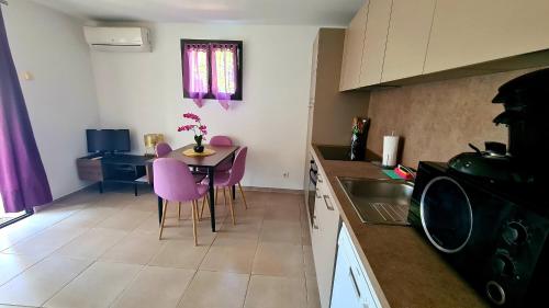 a kitchen with a table and purple chairs in a kitchen at Appartement Caroline in Sotta