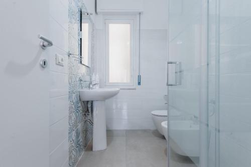 uma casa de banho branca com um lavatório e um WC em Rapisardi 188 Apartment by Wonderful Italy em Catânia