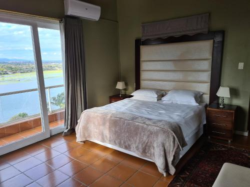 a bedroom with a large bed and a large window at Letamong in Hartbeespoort