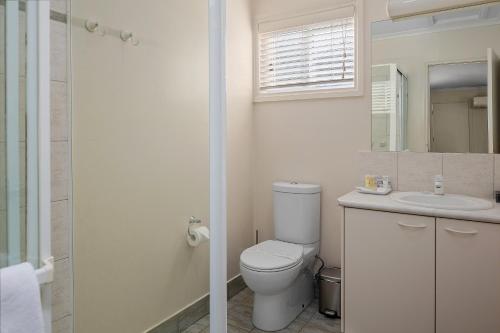 a white bathroom with a toilet and a sink at Yarra Gables in Healesville