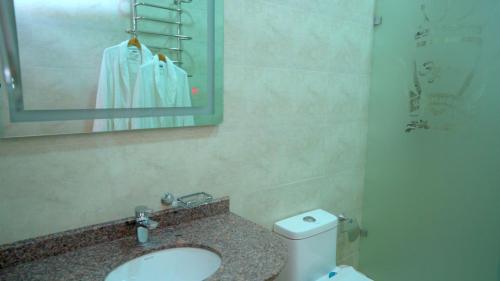 a bathroom with a sink and a toilet and a mirror at Edem Hotel Shymkent in Shymkent