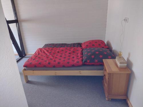 Ferien-in-ruhiger-Strasse-in-Stadtteil-von-Giessen في أوليمبياذا: سرير مع وسادتين حمراء في الغرفة