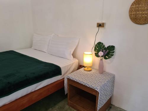 a bedroom with a bed and a table with a lamp at Phangan Villa Bungalows in Thongsala