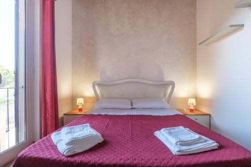 a bedroom with a pink bed with two towels on it at Casa Vacanza Josephine in Barcellona-Pozzo di Gotto