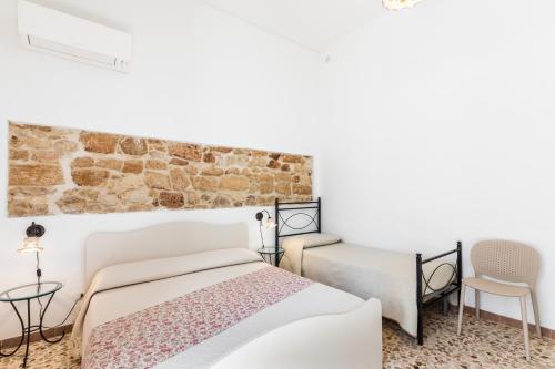 a bedroom with two beds and a brick wall at Morfeo Charming Rooms & Relax in Avola