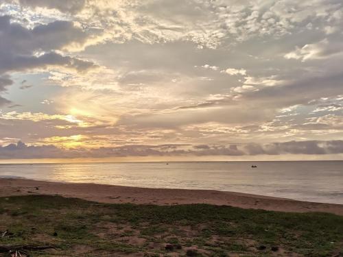 a beach with a cloudy sky and the ocean at Helios Beach Resort in Tangalle